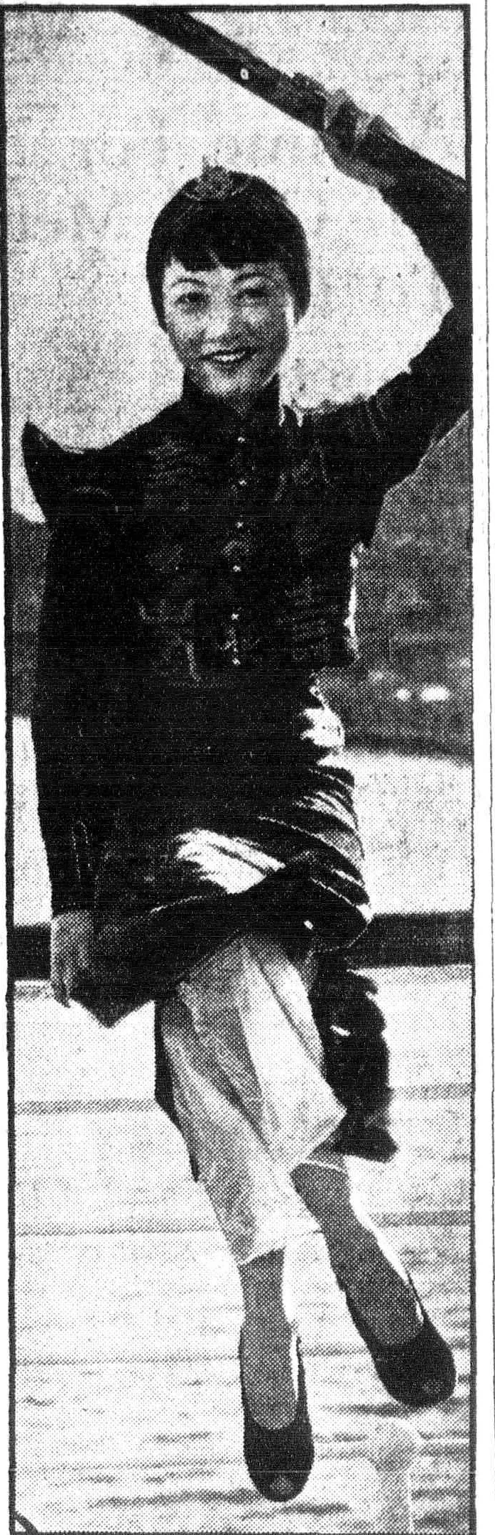Anna May Wong perched on the ship's rail, one arm raised to the rigging, smiling, in a dark Chinese tunic over pale trousers.