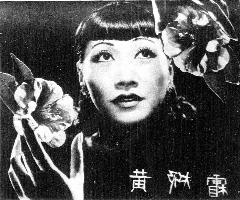 Anna May Wong's face framed by camellias, a camellia in her raised hand, her Chinese name lettered at lower right.